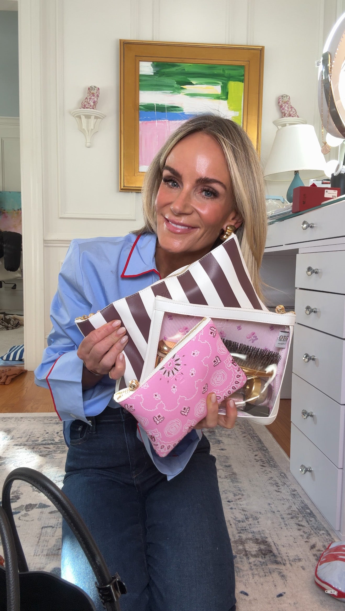 Meeghan Mullin holding OTG collaboration bags in a room with furniture and decor.